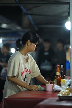 A woman cleaning a table in a Bali restaurant, with focus on cleanliness and service.