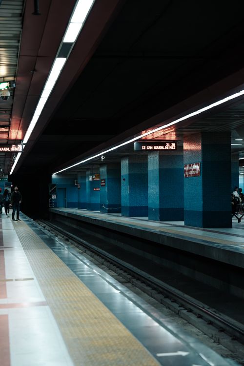 Free Dimly lit Ankara metro station with blue pillars and tracks at night. Stock Photo
