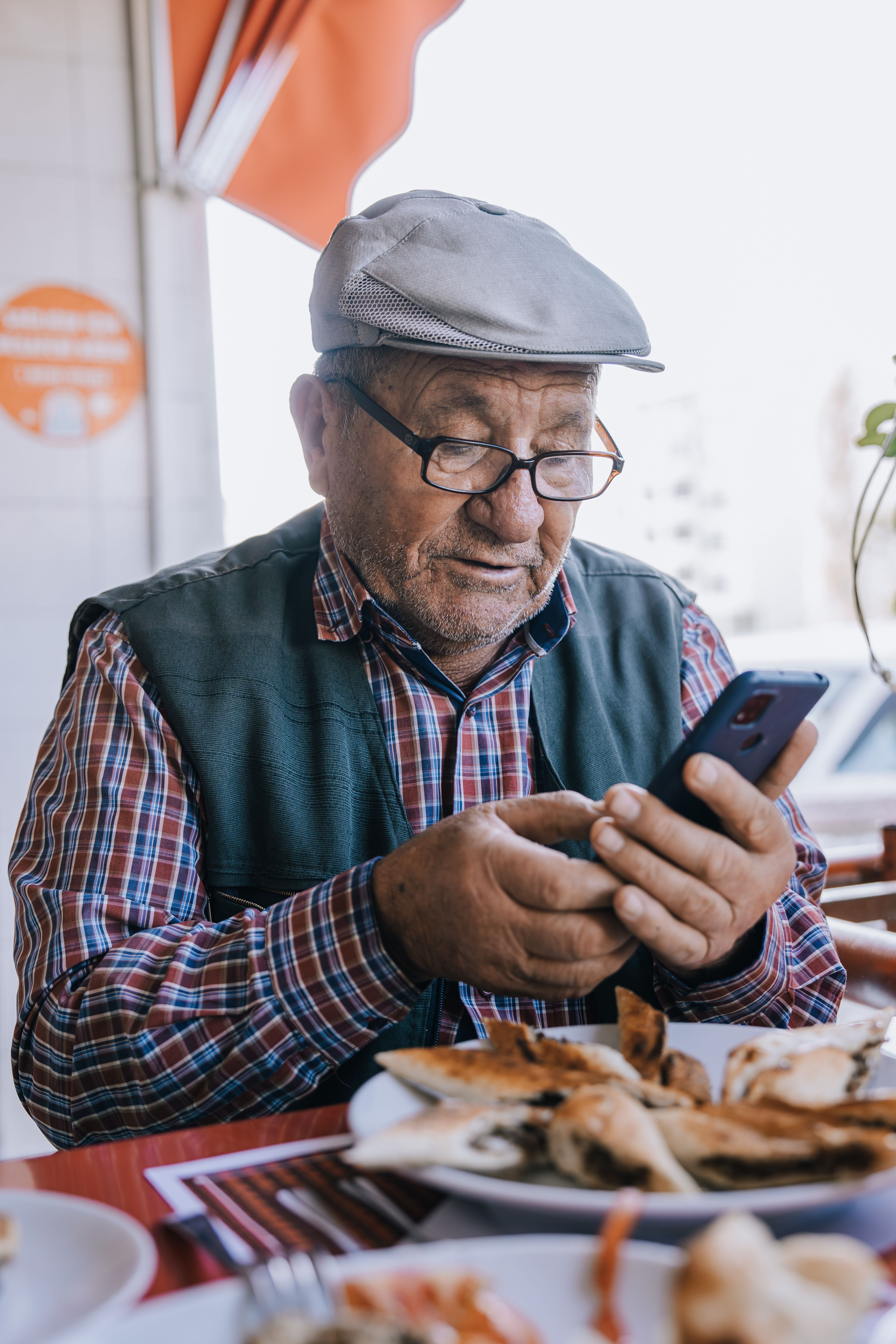 Senior man with smartphone enjoying meal outdoors at a restaurant in Ankara, Turkey.