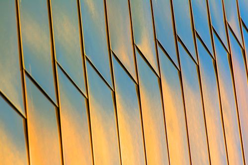 Free Golden reflections on a modern building's metal facade during sunset, creating a stunning pattern. Stock Photo