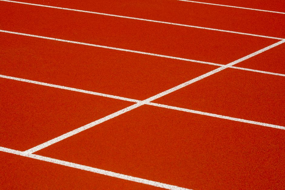 Close-up of a red running track with white lines, showcasing sports infrastructure.