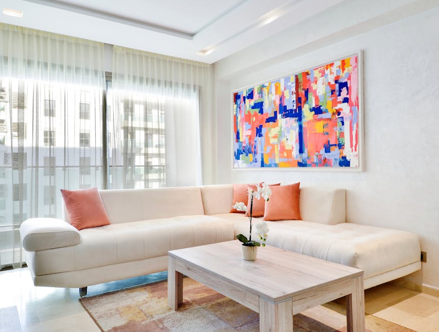 Bright and modern living room featuring abstract art, a neutral sofa, and a houseplant on the coffee table.