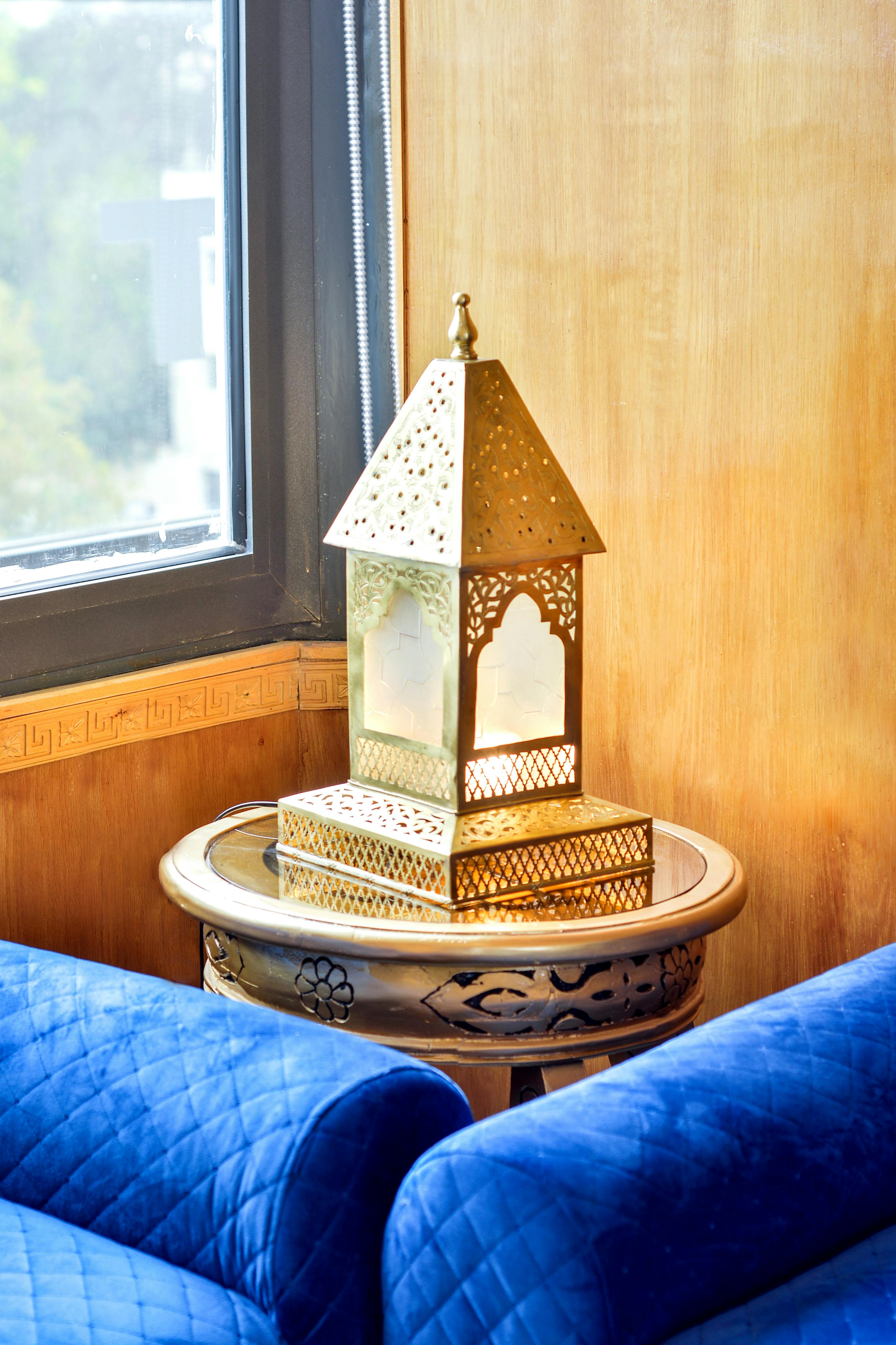 Free Stylish blue armchairs with a decorative golden lantern on a round table by a window. Stock Photo