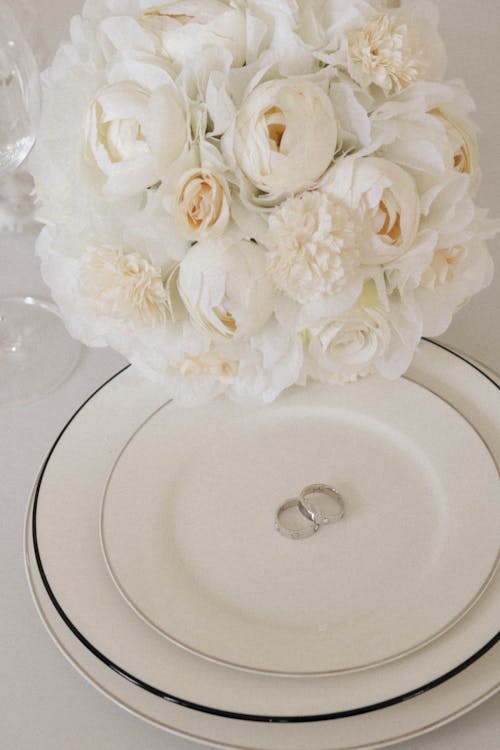 White Flower Bouquet and Wedding Rings on a Plate
