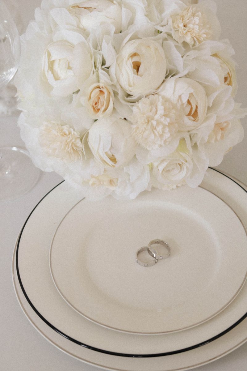 Wedding rings on a plate beside white flowers
