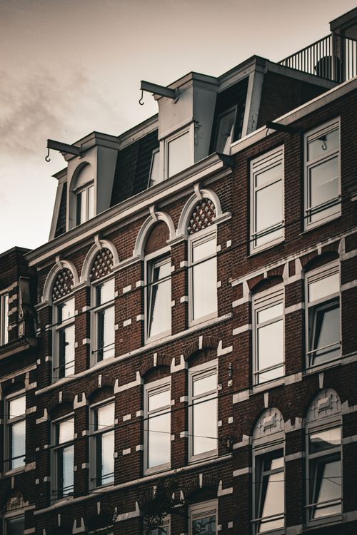 Free A beautiful view of traditional Amsterdam architecture captured during the evening, showcasing intricate brickwork and design. Stock Photo