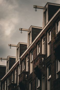 Classic Amsterdam architecture featuring brick facades and traditional gable hooks, captured on a cloudy day.