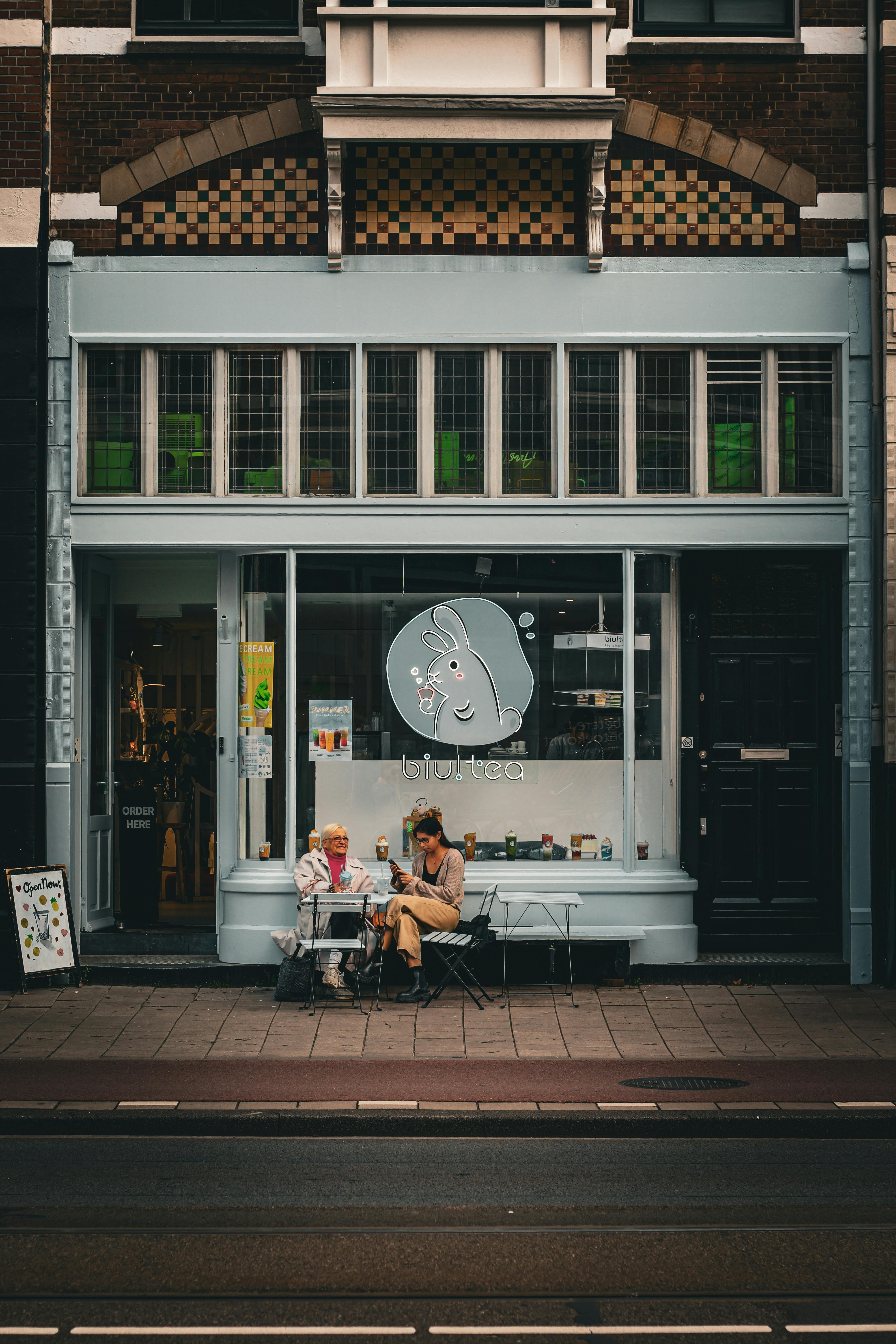 Charming street view of a couple enjoying drinks outside a café in Amsterdam.