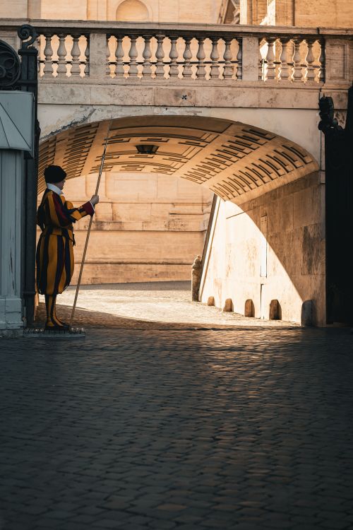 Free Swiss Guard in traditional uniform standing by an archway inside Vatican City, Rome, Italy. Stock Photo