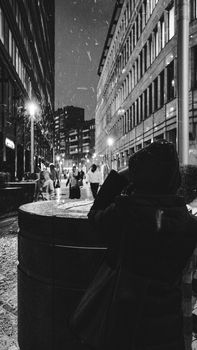 Black and white photo capturing a snowy winter night on urban city streets.