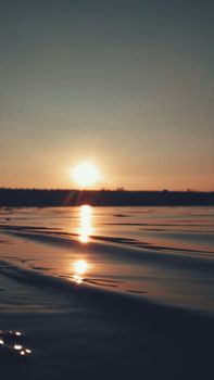 A calming sunset over tranquil sea waters, with golden reflections on the waves.