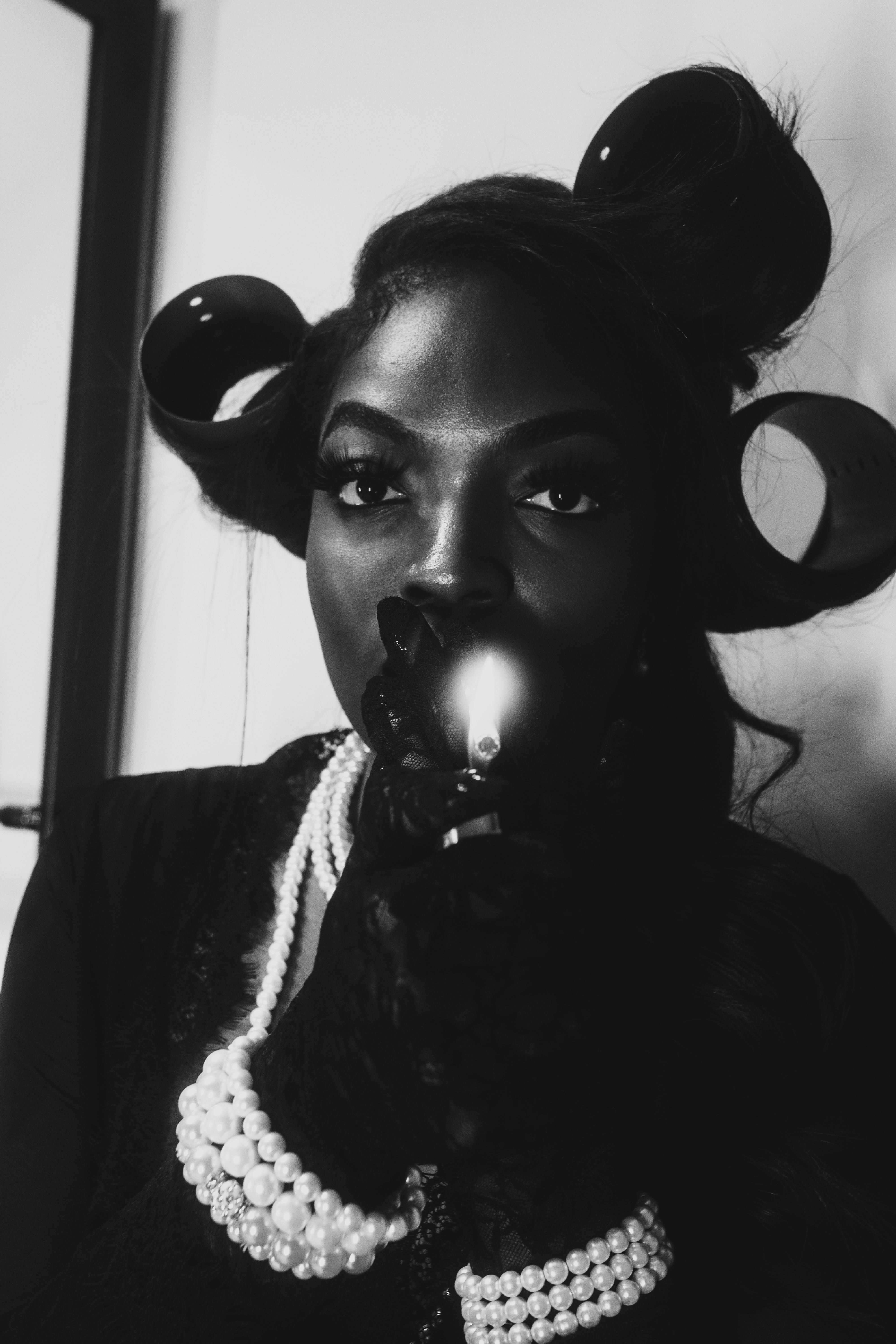 Artistic black and white portrait of a woman with vintage curls and pearls, evoking classic elegance.
