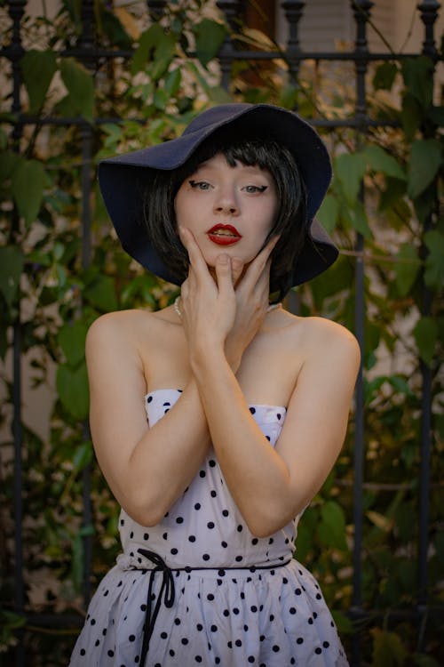 Young Woman in a Dotted Dress Standing with her Head in Hands 