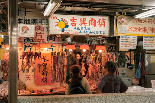 Bustling market stall showcasing raw meat selections in an Asian urban setting with shoppers browsing.
