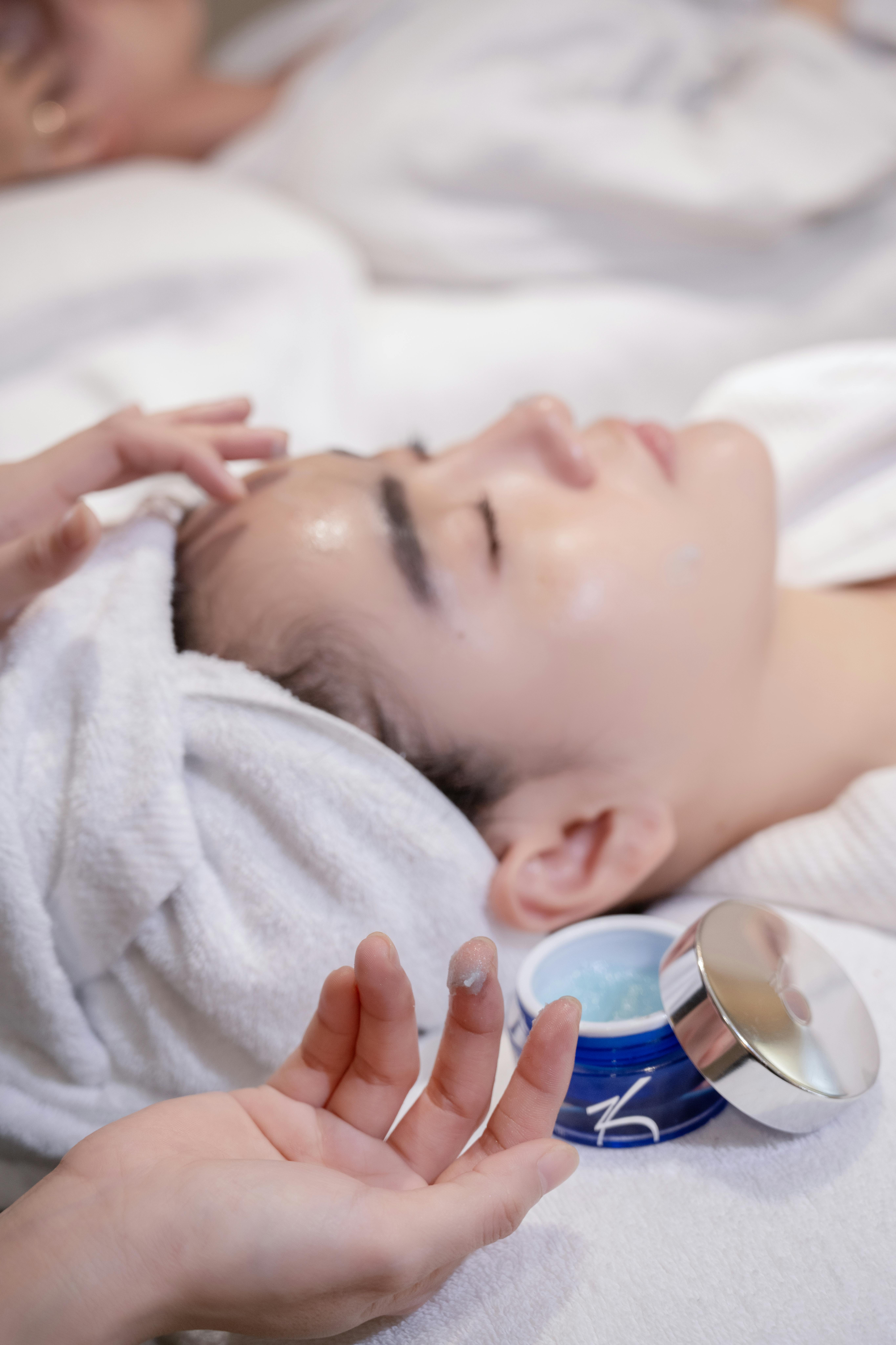 Woman receiving a soothing facial treatment in a spa setting, promoting skincare and relaxation.