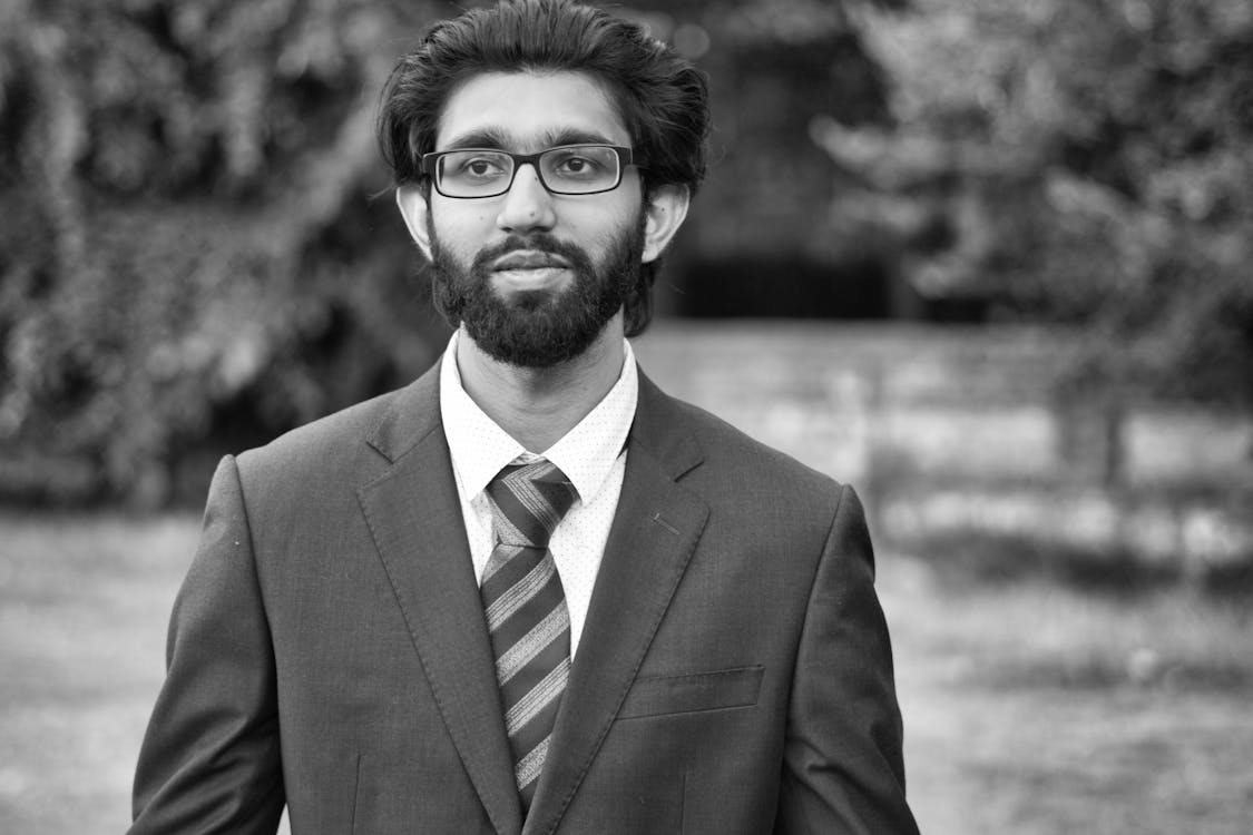 Black and White Photo of a Bearded Man in a Suit Standing Outside 