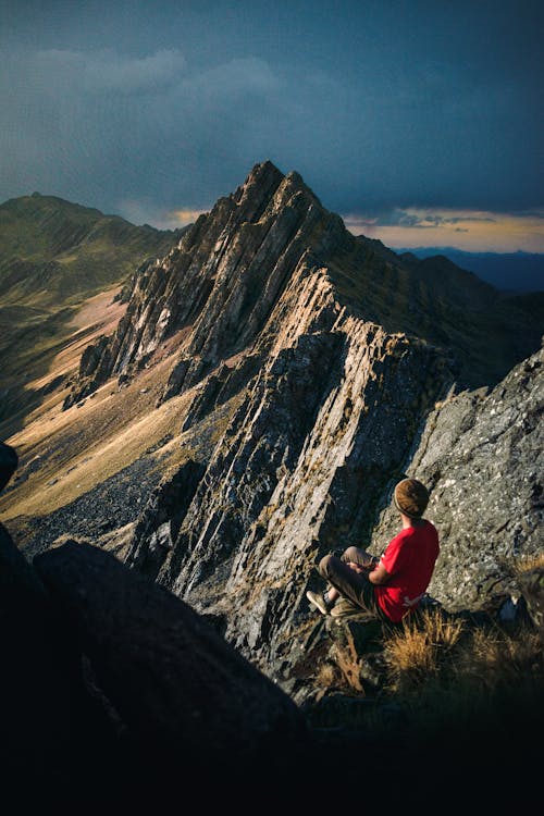 A Person Sitting on a Rocky Mountain Peak 