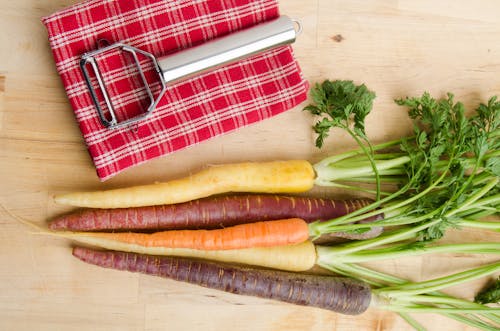 Variety of Carrots and a Peeler Lying on a Cloth 