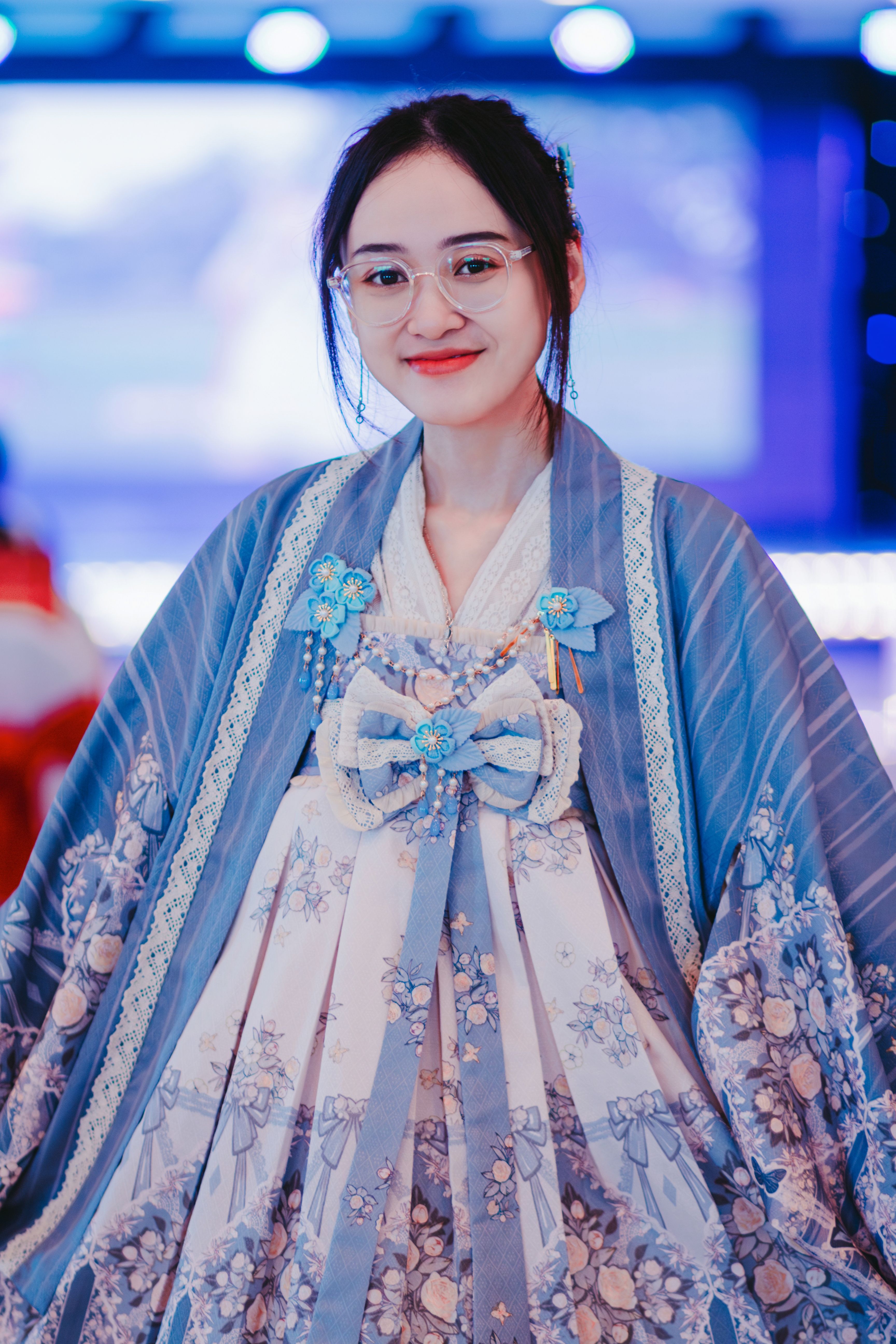 Portrait of a smiling woman in blue traditional dress at a cultural event.