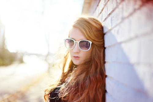 Woman Wearing White Sunglasses Leaning on Wall on Focus Photo