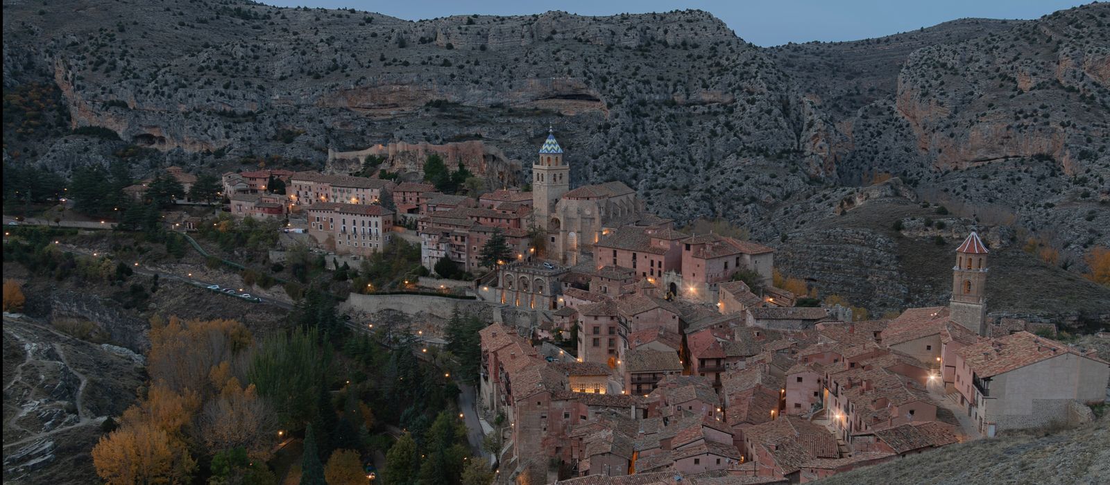 Aerial view of Teruel, Spain's historic architecture during twilight, highlighting townscape and mountains.