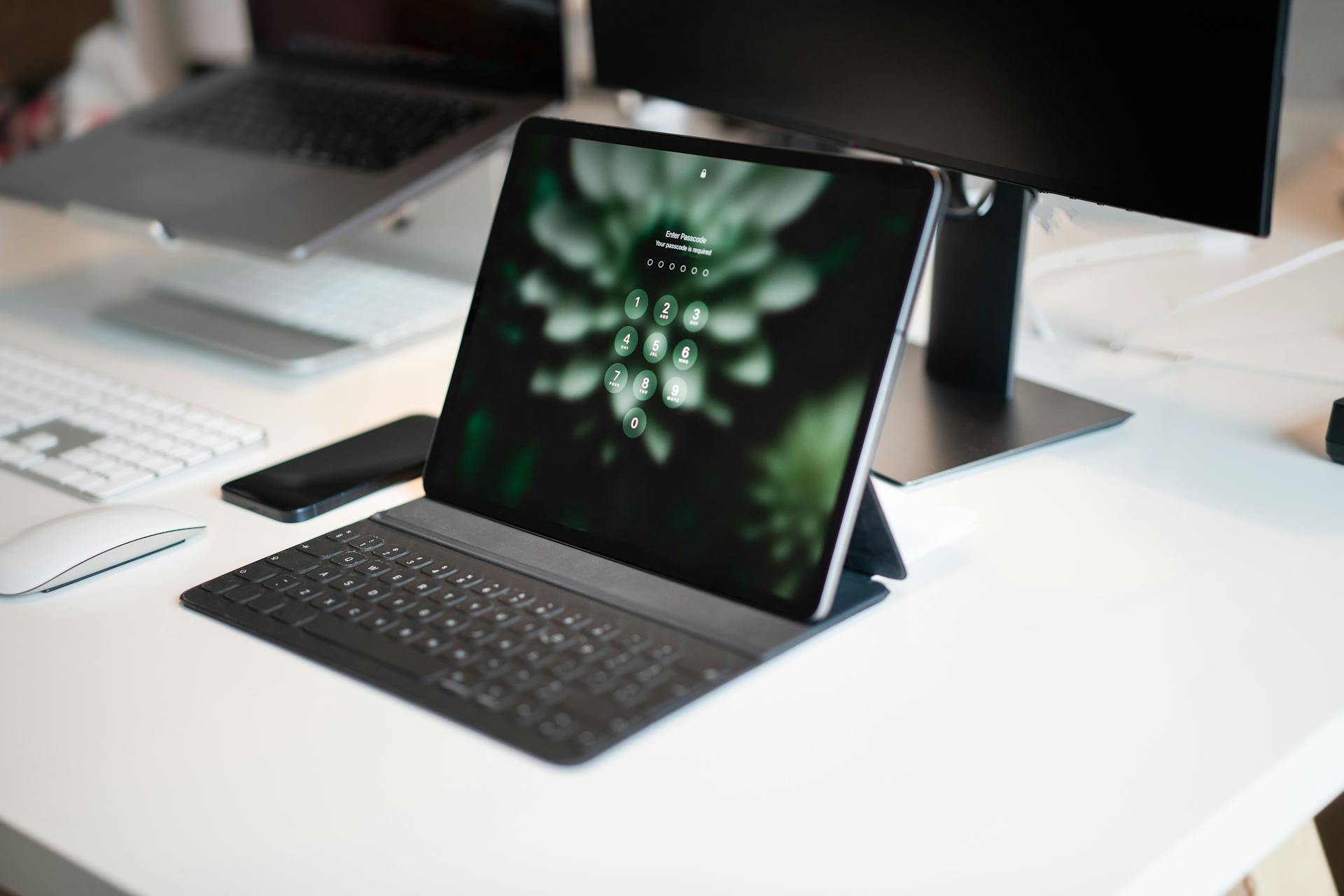 A sleek modern office setup featuring a tablet with keyboard, desktop monitor, and accessories.