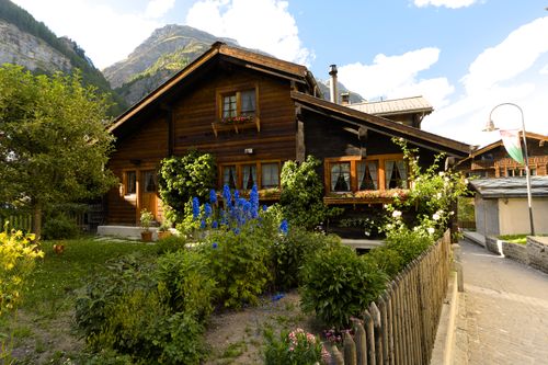 Free Cozy wooden chalet surrounded by lush garden in picturesque Zermatt under clear skies. Stock Photo