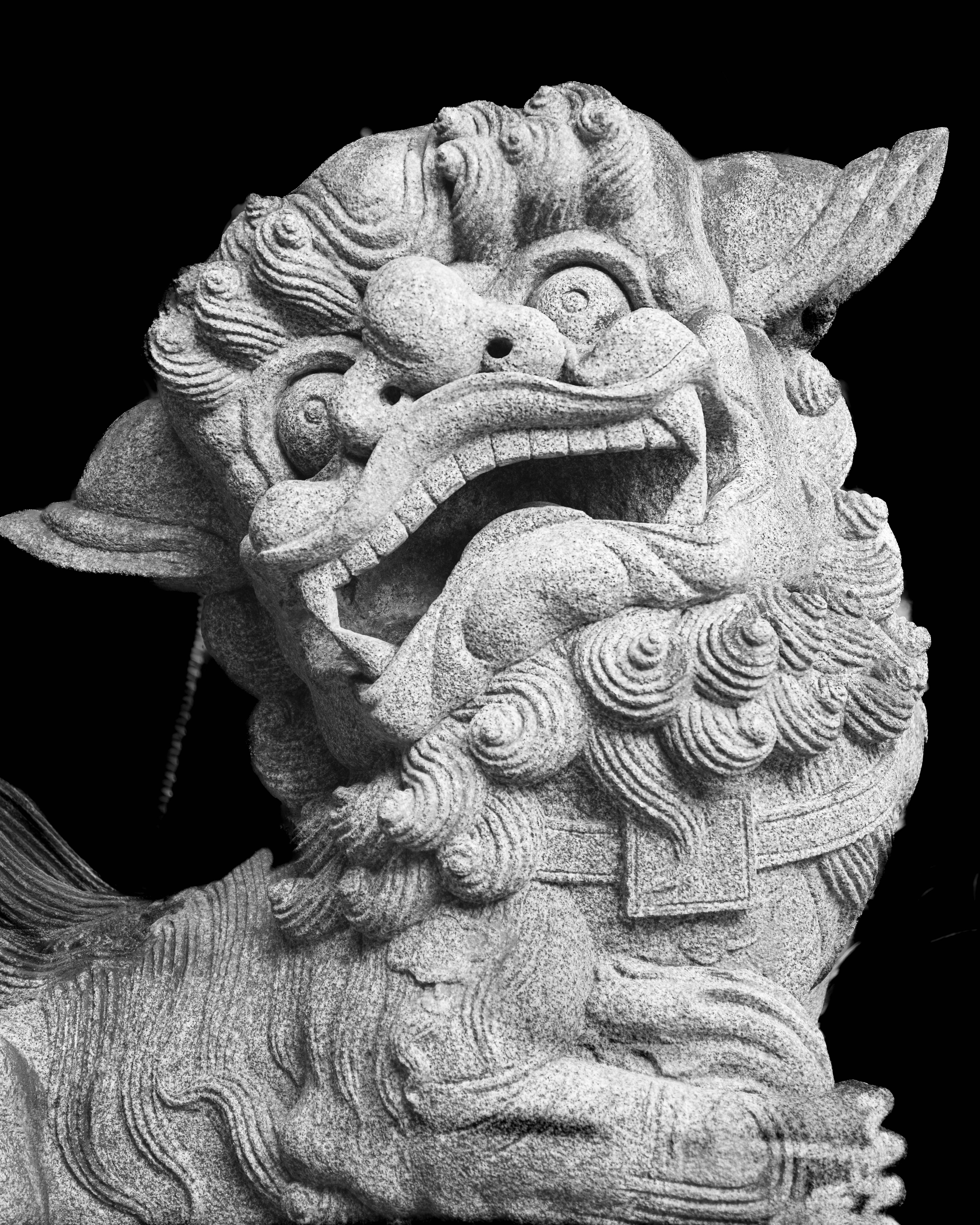 Detailed stone dragon sculpture on black background embodies Chinese mythology.