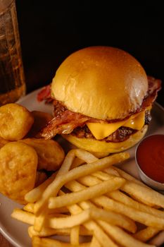 Tasty cheeseburger with bacon, nuggets, fries, and ketchup served on a plate.