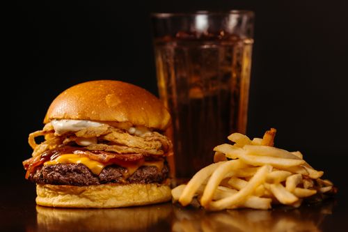 Free Savor a juicy cheeseburger with onion rings, fries, and a refreshing soft drink. Stock Photo