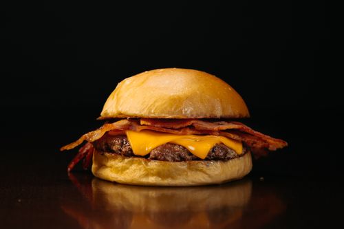 Free Tasty bacon cheeseburger on a dark background, perfect for food photography. Stock Photo