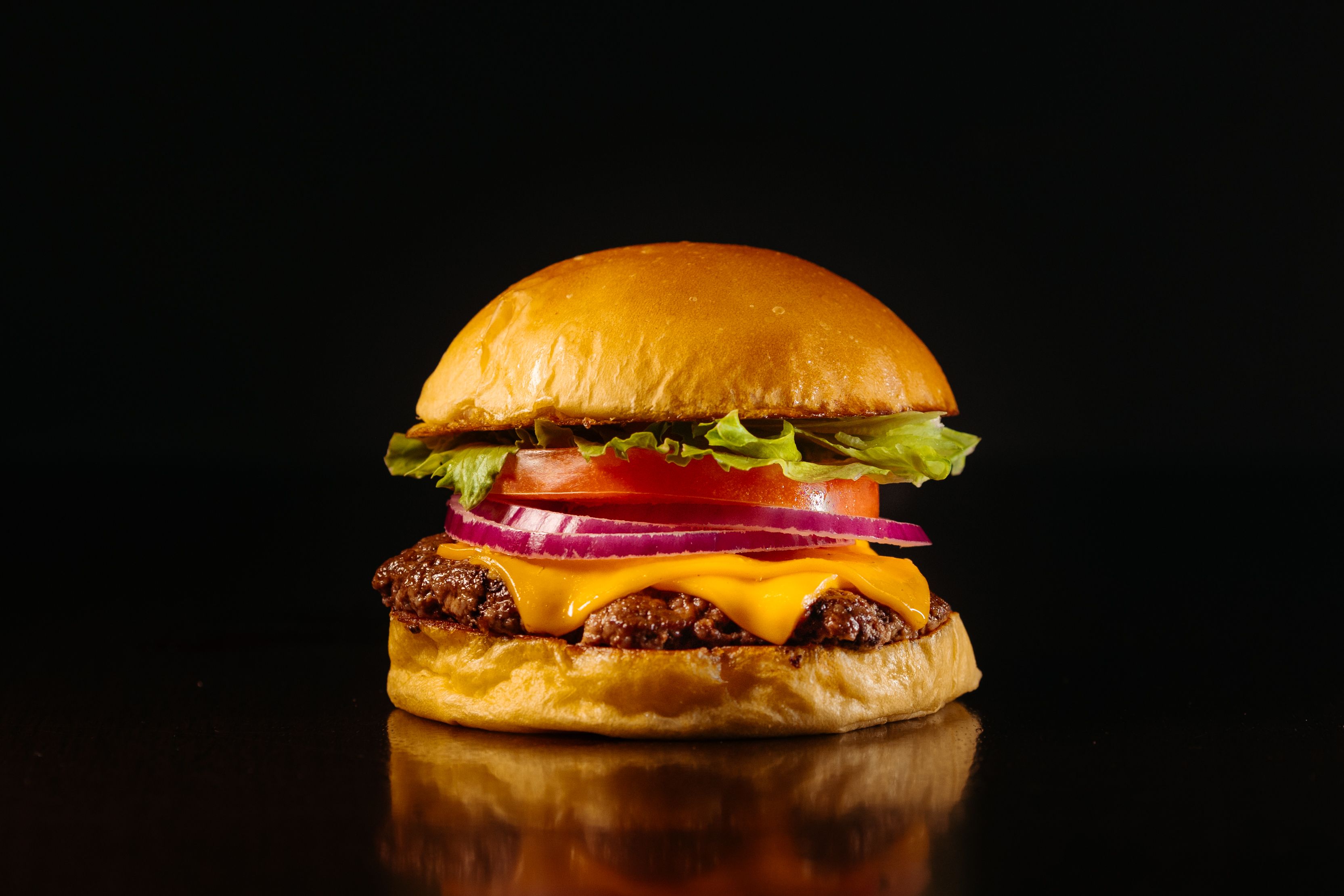 Delicious cheeseburger with fresh ingredients on a dark background, perfect for food lovers.