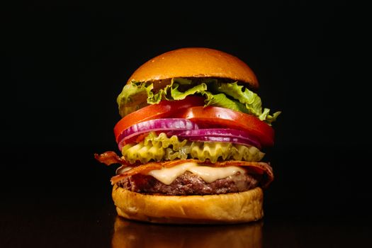 Juicy cheeseburger with fresh lettuce, tomato, onions, and pickle slices.