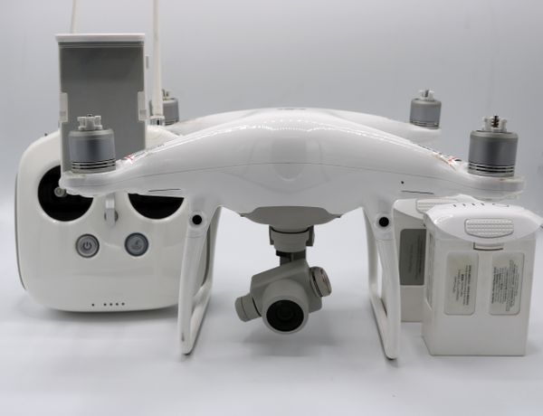 White quadcopter beside its controller and spare batteries — photo by Bedirhan Akyüz on Pexels