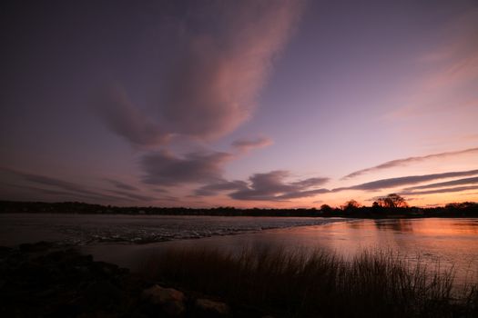Beautiful twilight sky reflecting on a tranquil lake surrounded by nature's silhouettes.