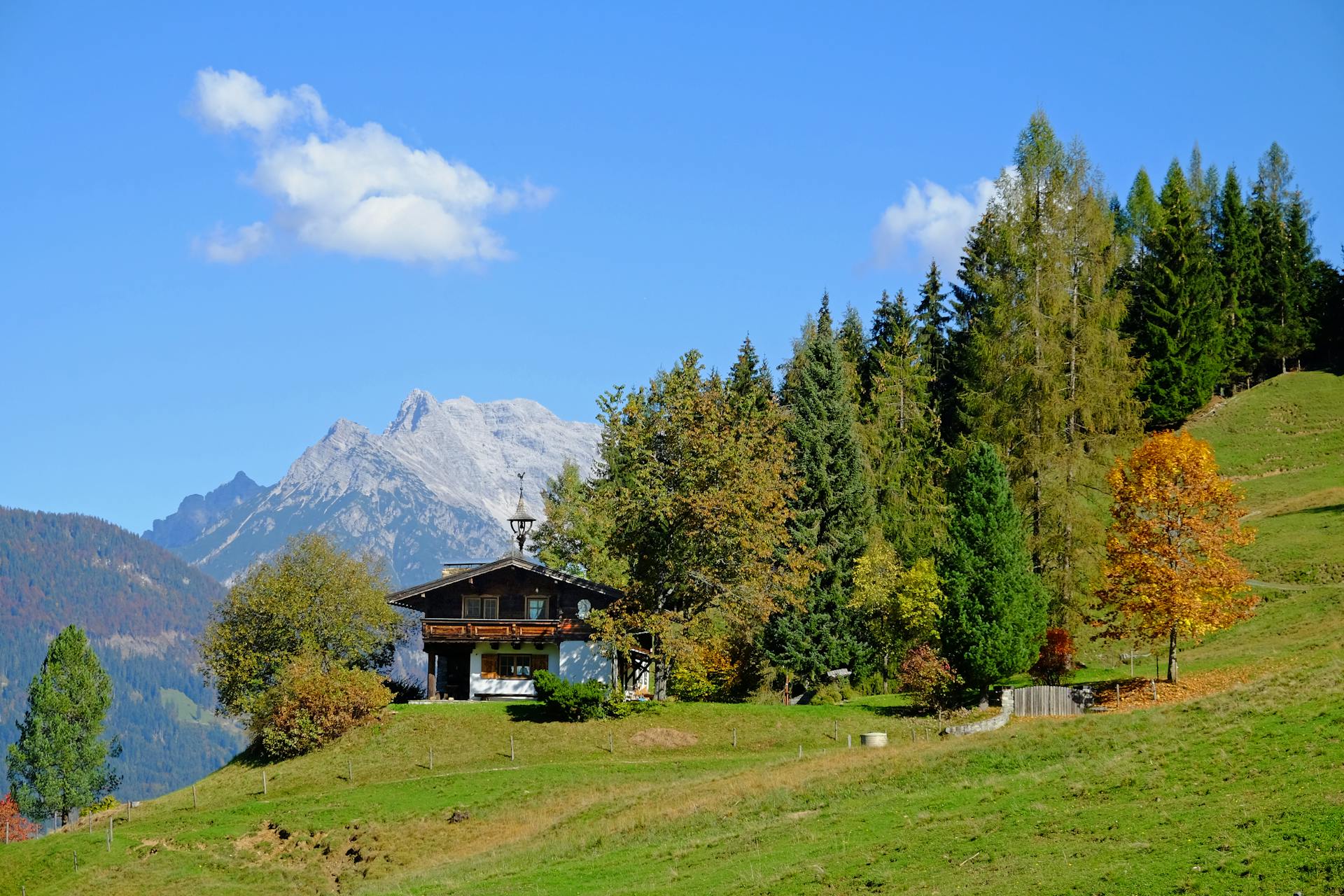 Picturesque Alpine chalet surrounded by vibrant fall foliage in the Tirol mountains.