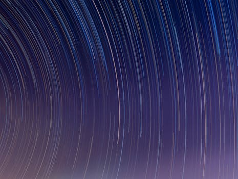 Curved star trails captured in a long exposure night sky, showcasing celestial movement.