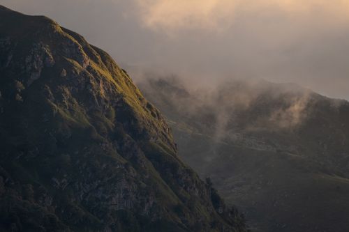 Free A serene view of a mist-covered mountain peak at twilight, showcasing rugged cliffs and fog. Stock Photo