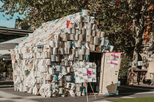 Unique architectural structure made entirely of books, showcasing creativity and literature in an urban outdoor location.