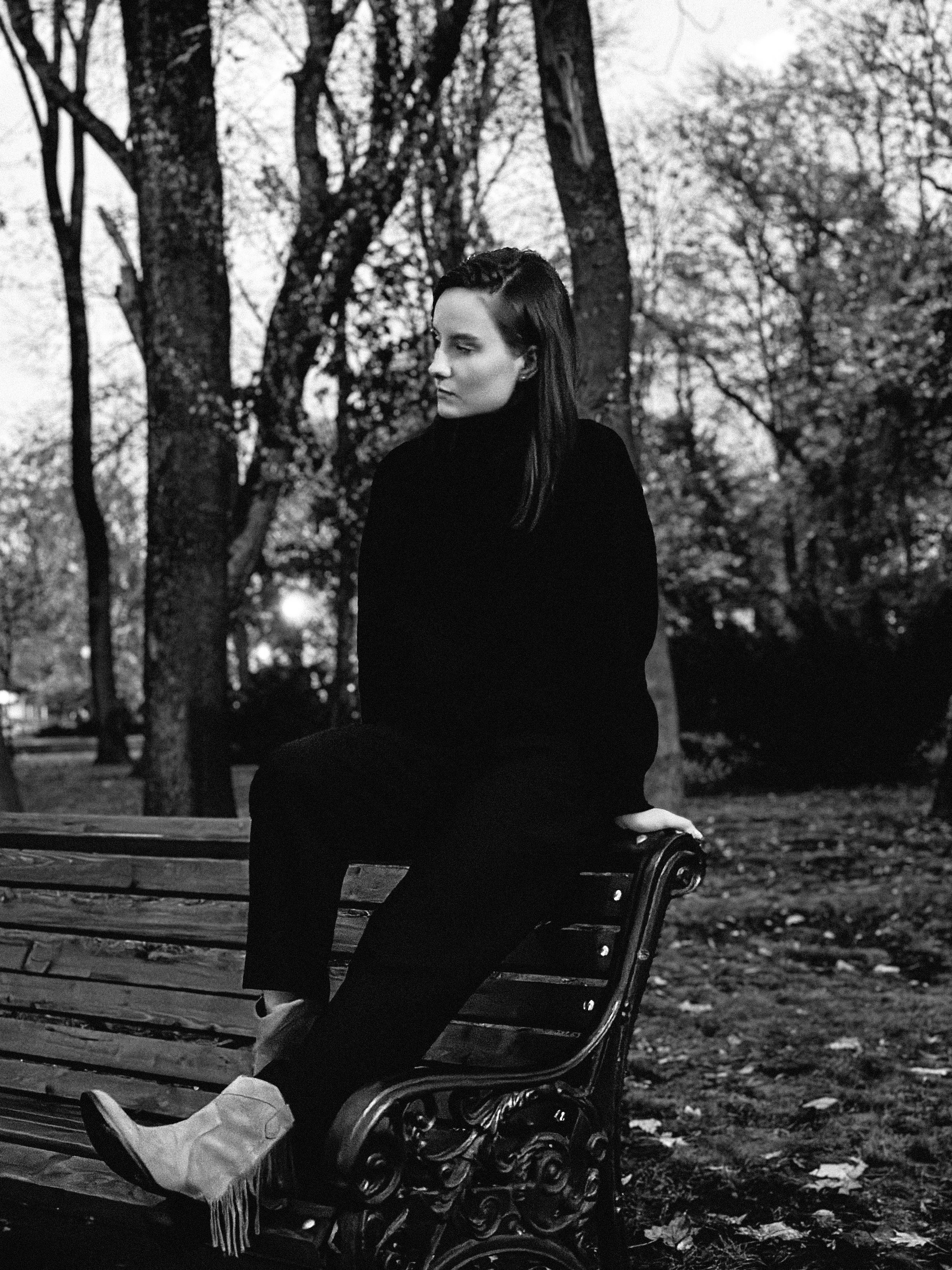Black and white photo of a woman sitting on a park bench in Krasnodar.