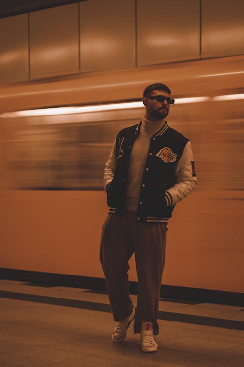 Model in Varsity Jacket over a Turtleneck and Loose Pants on a Subway Platform