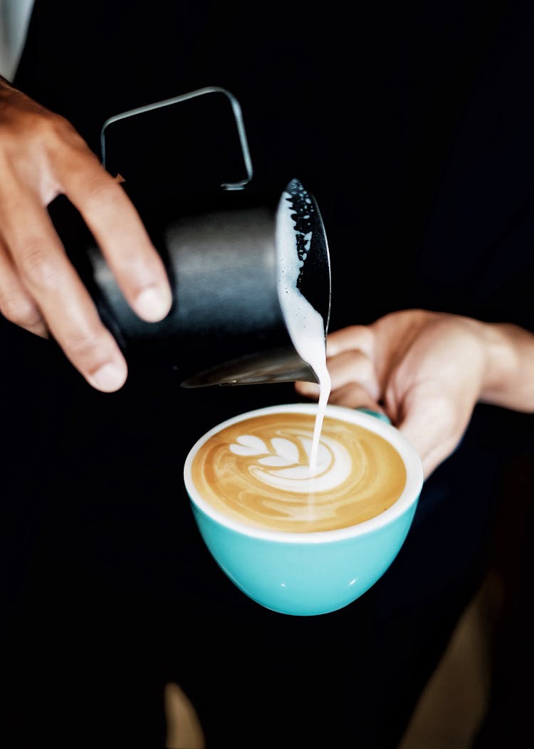 Person Pouring Coffee Latte On Ceramic Mug