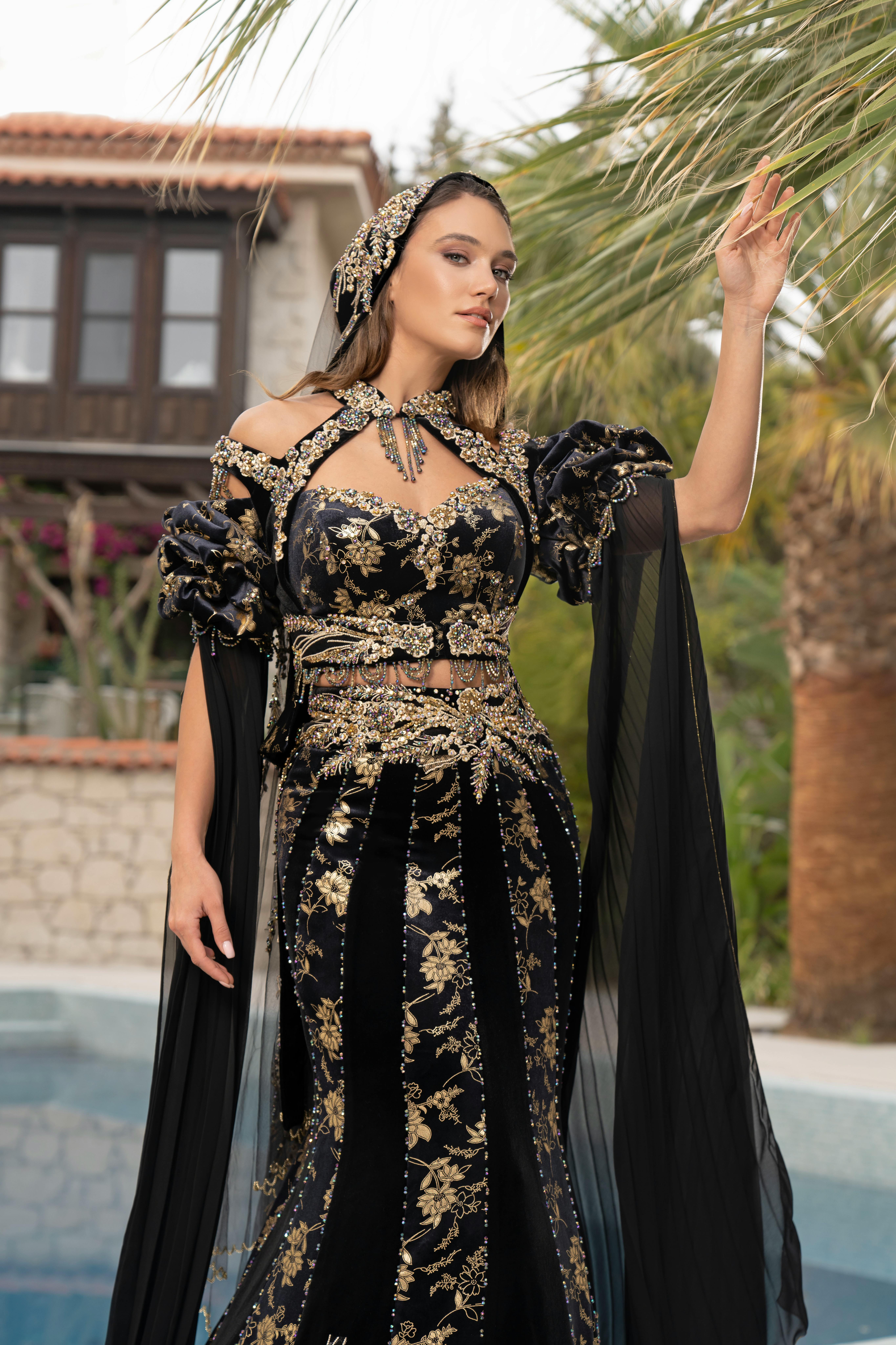 Woman in elaborate black and gold dress posing outdoors at a villa in İzmir.
