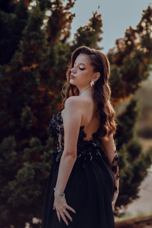 Elegant Woman in a Black Dress Posing Outside 