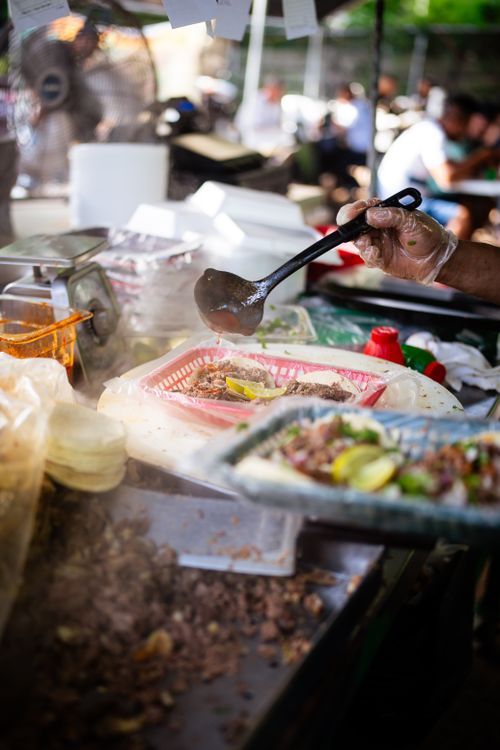 Free Close-up of a street food vendor preparing fresh tacos with vibrant ingredients. Stock Photo