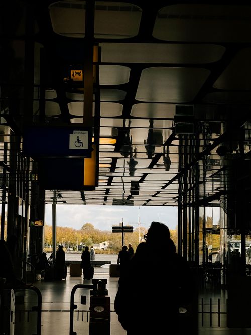 Free Silhouetted people walking through transportation hub in Amsterdam with a backlit background. Stock Photo