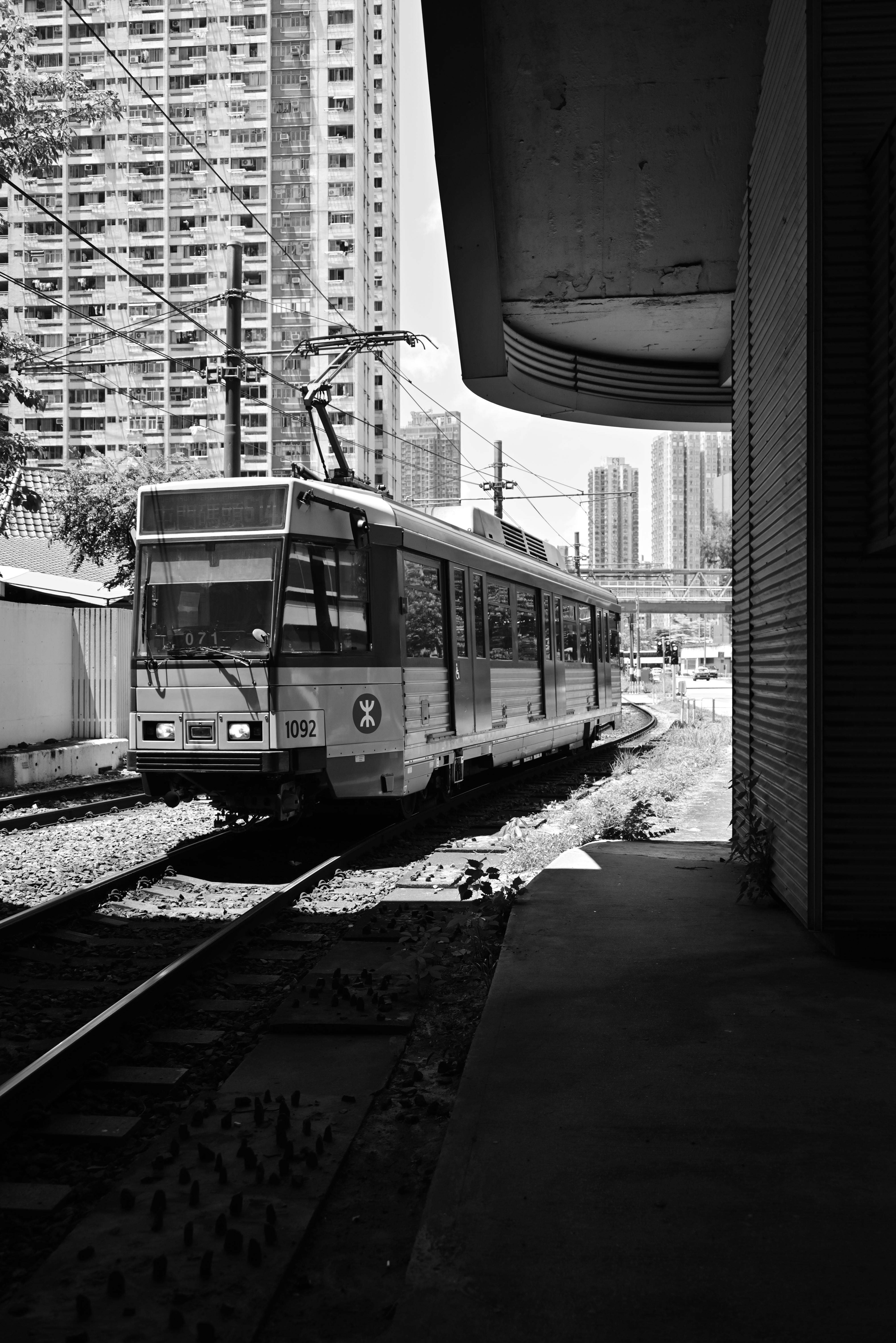An urban train navigates through a cityscape, captured in striking black and white.