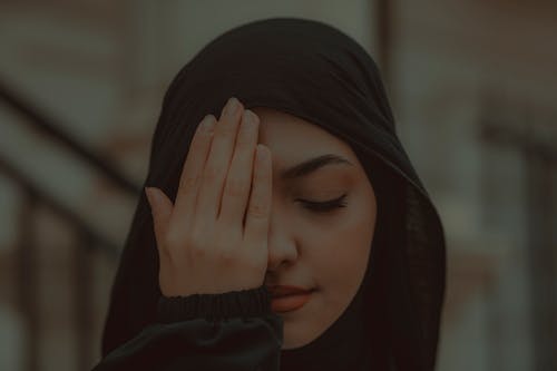 Dark Photo of a Muslim Girl Covering Her Eye with a Hand