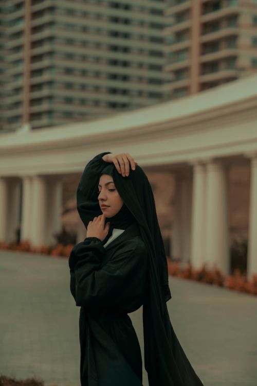 Free Elegant portrait of a woman with eyes closed, standing in an urban environment with modern architecture. Stock Photo