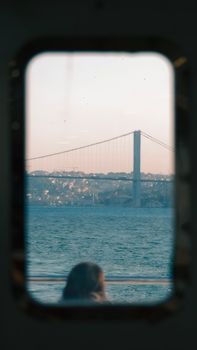 A scenic bridge viewed through a ferry window at sunset, capturing urban tranquility.